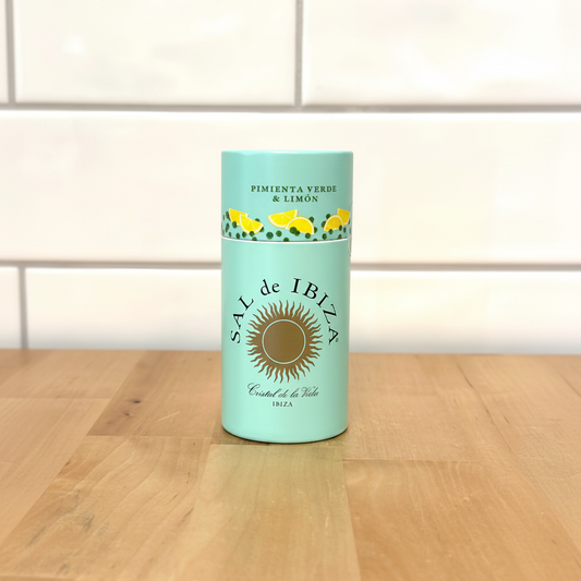 Sal de Ibiza Granito Lemon shaker sobre superficie de madera con pared de azulejos blancos