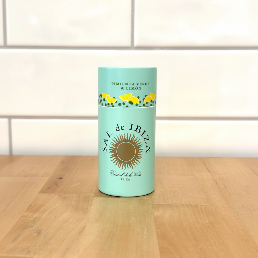 Sal de Ibiza Granito Lemon shaker sobre superficie de madera con pared de azulejos blancos
